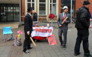Infotisch der PARTEI mit baseballschlägerbewaffneten Genossen.